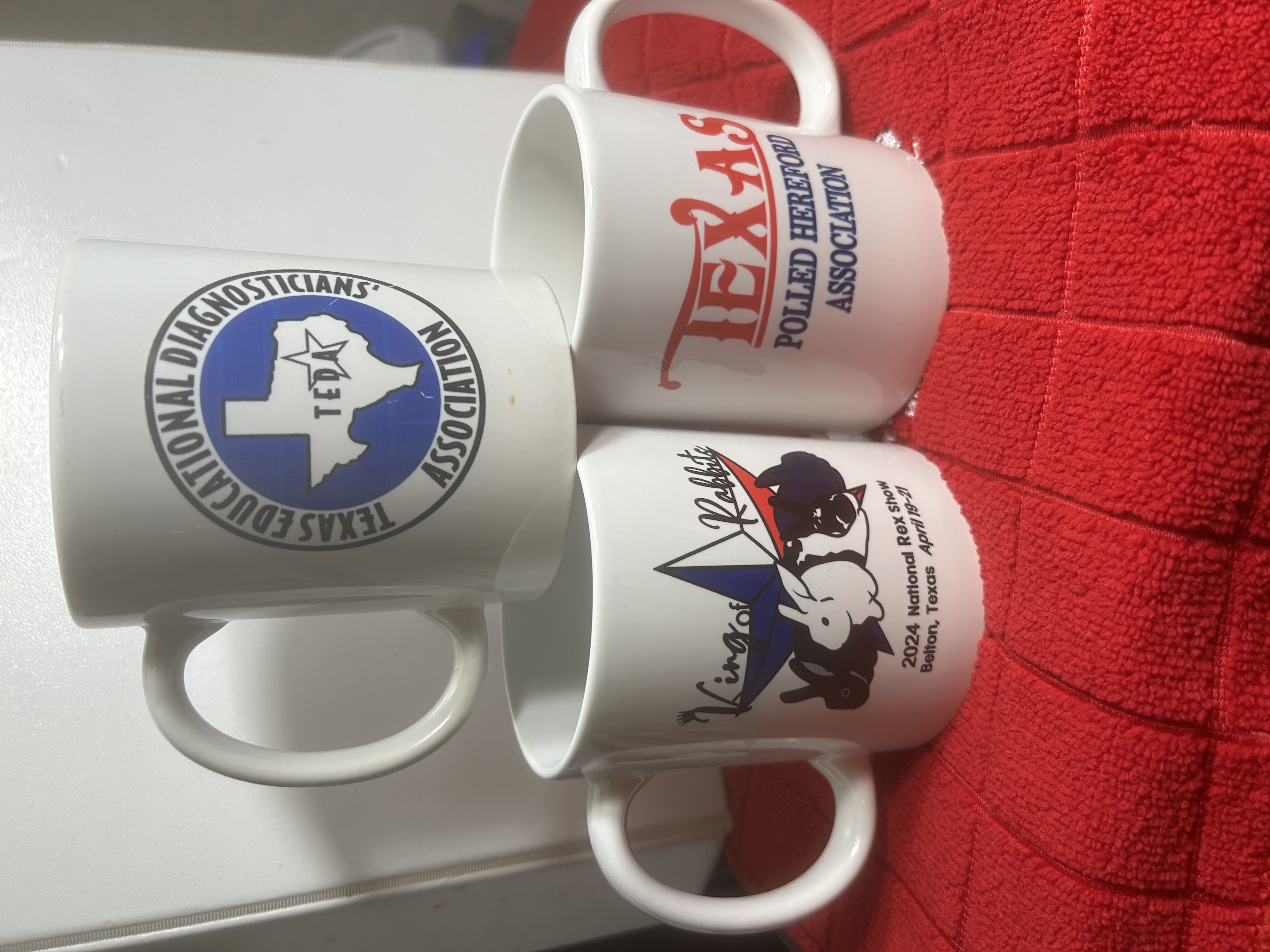 Three coffee mugs with various Texas association logos